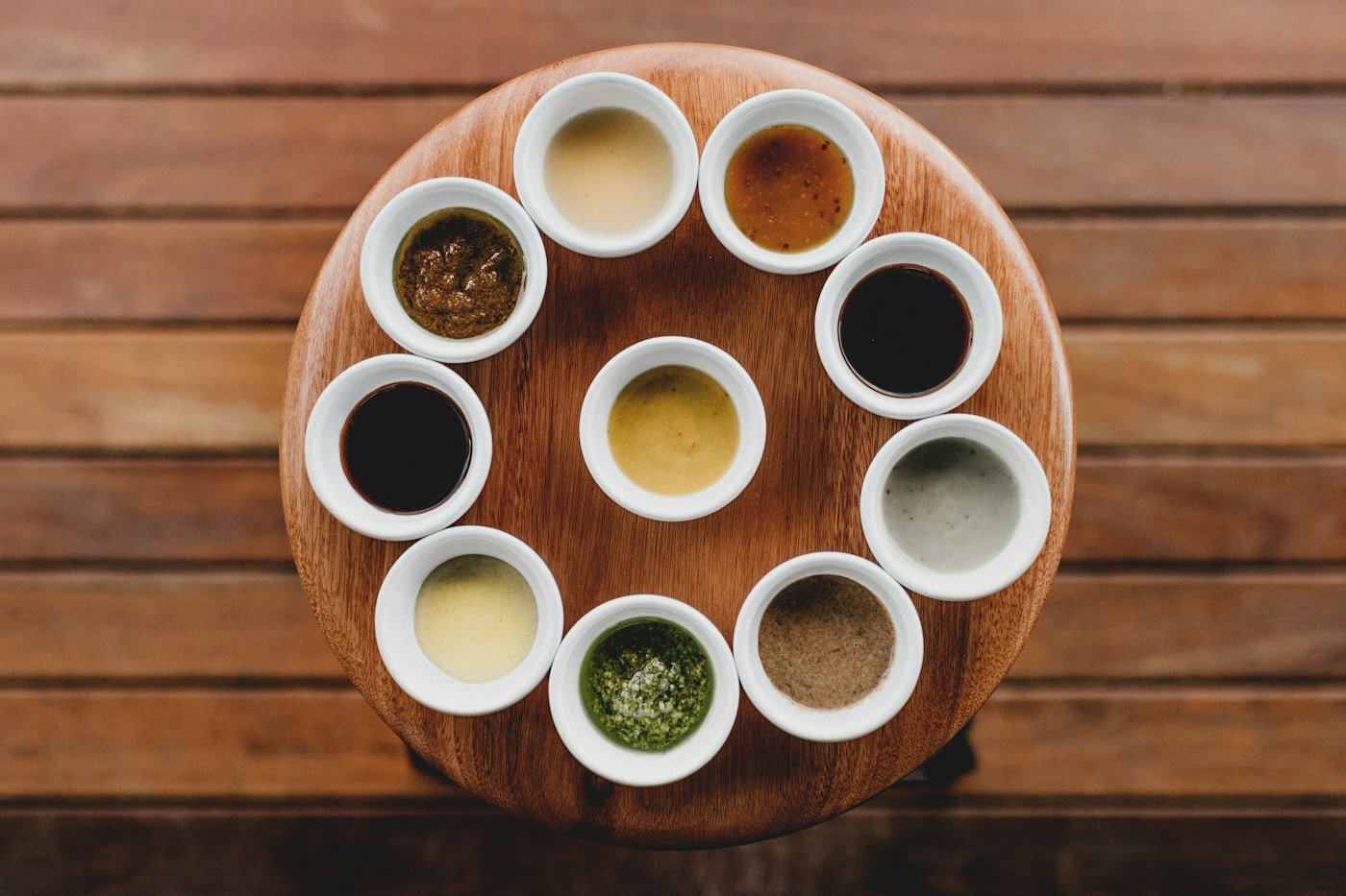 Assorted sauces in small bowls on a wooden serving board