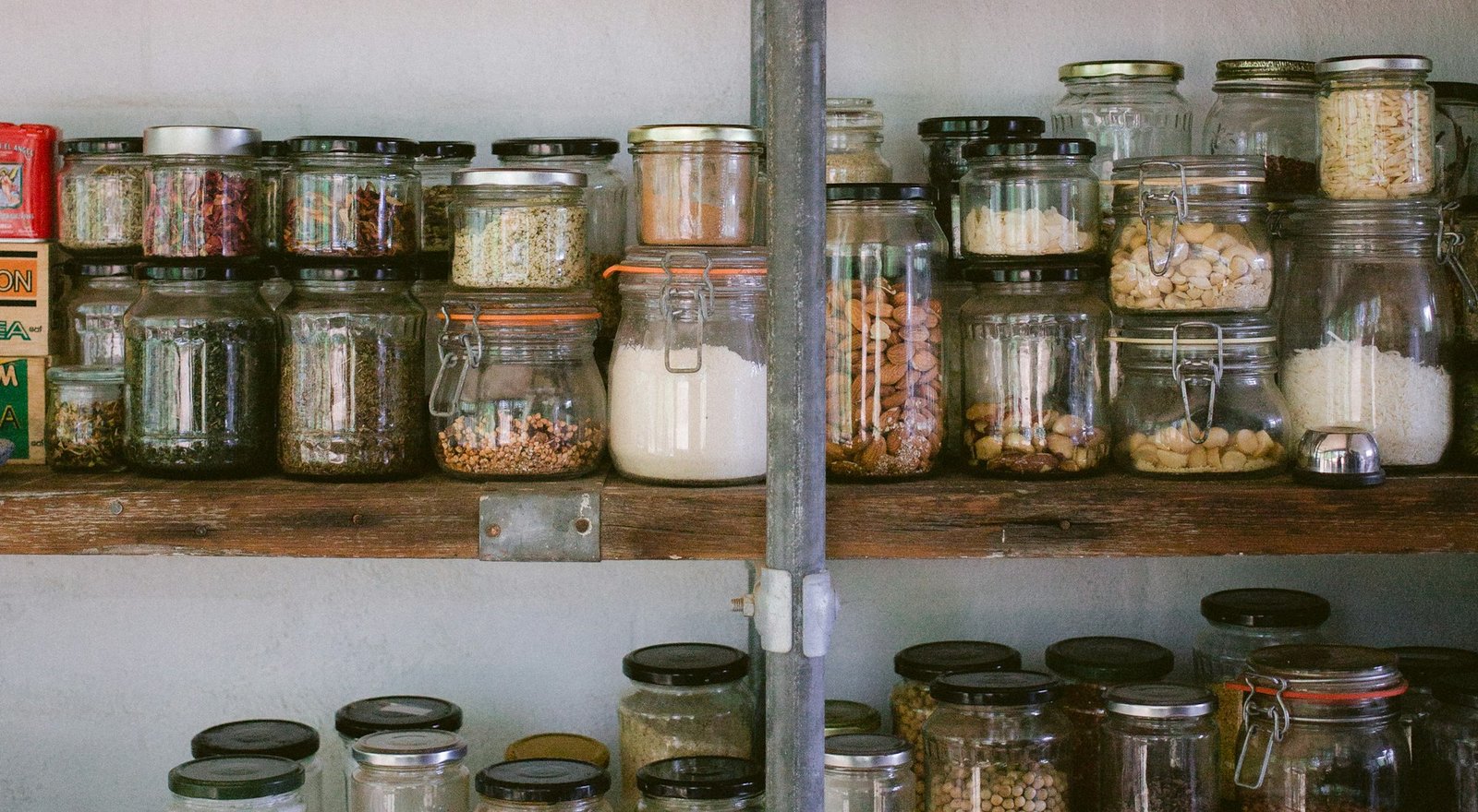 Wooden shelves stacked with glass jars of spices, nuts, grains and rice